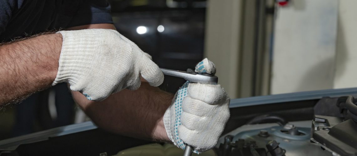 Close up hands in white textile gloves of mechanic doing car service